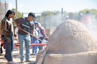 middle school students tend to a kiva oven