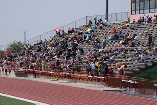 The stadium with the bleachers filled one-third with sports fans.