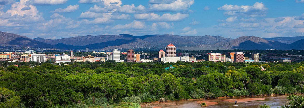 Panorama view of downtown Albuquerque with the Rio Grande in the foreground.