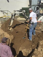 Heavy equipment operator assists in replacing a water line