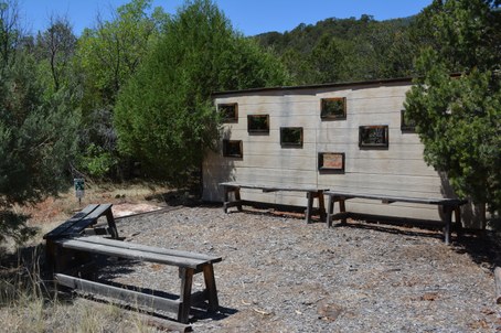 Bird blind wall with rectangle cutouts at different heights and wood benches in front
