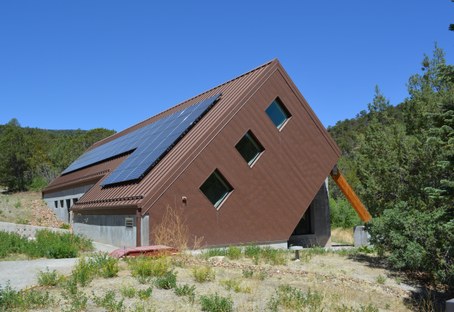 Brown building that looks from outside like it's on a 45 degree angle with wood beam holding it up on side