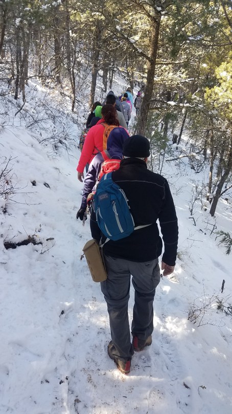 Class with volunteer Frank in back of line walking down snowy trail
