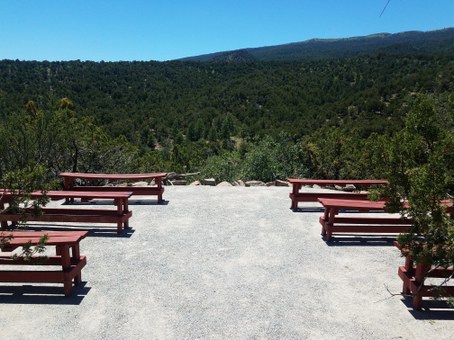 Red benches on gravel surface with mountain view covered in green trees