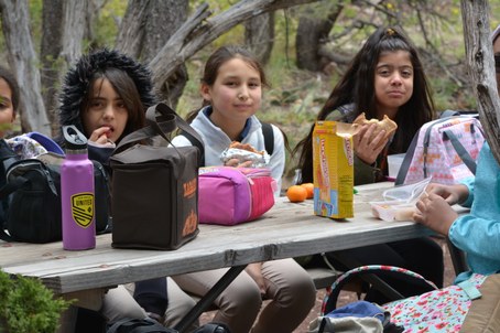 Three students at picnic table eating lunches