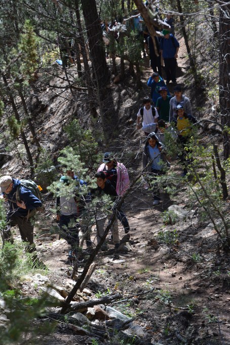 Vince leading class of student up trail through forest