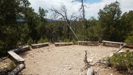 Wood benches in circle around rocky ground with trees surrounding