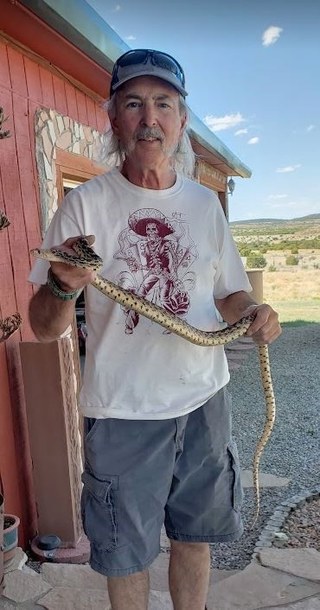Al Youberg, pictured here holding a snake, is a volunteer at the Sandia Mountain Natural History Center.