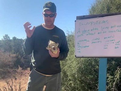 Volunteer Daniel teaching in front of a whiteboard at an outdoor classroom.